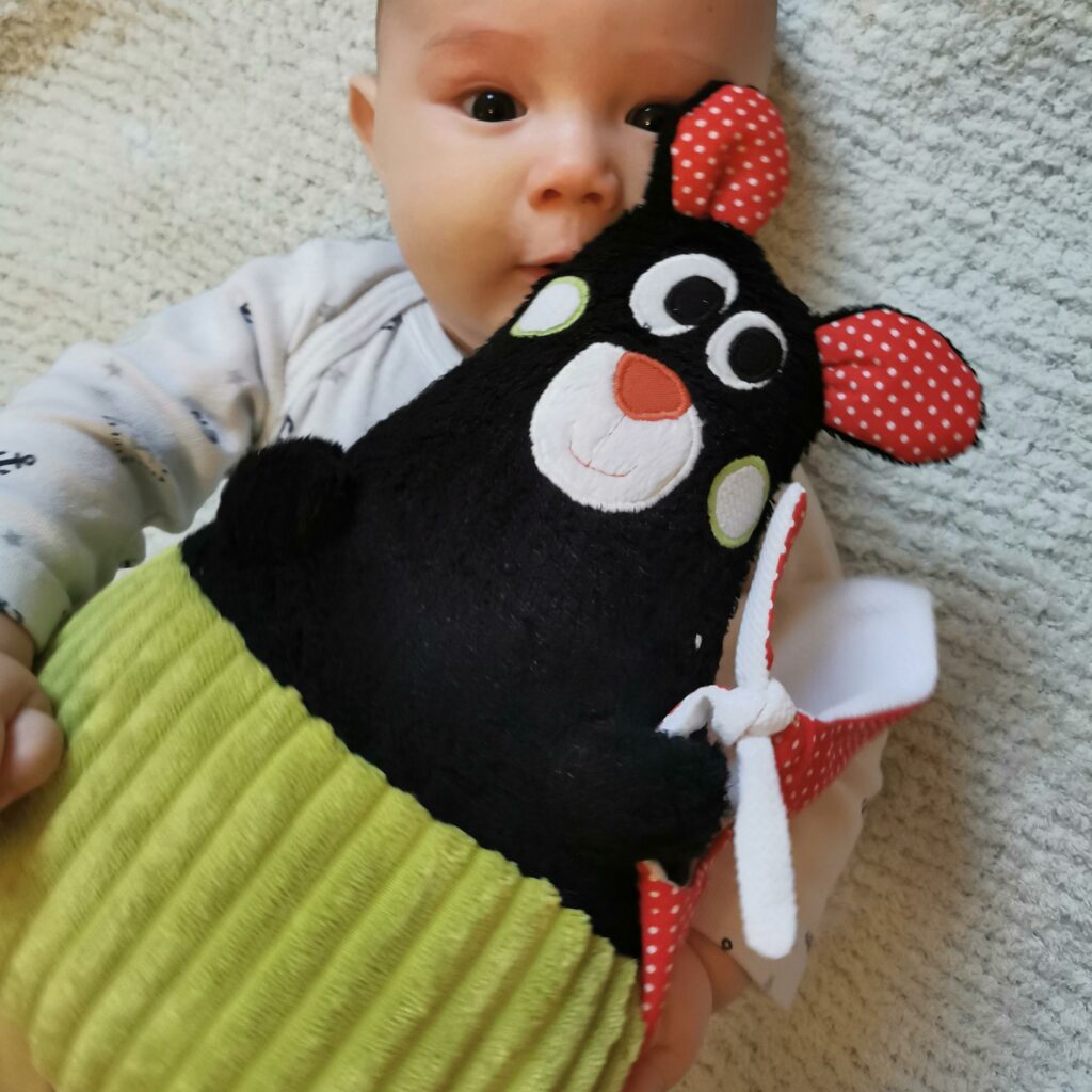 bébé et doudou pour bébé fabriqué en France de manière artisanale dodu qui se font un câlin, le dodu est noir avec la culotte vert pomme et les oreilles rouges, une création 2 pommes et un mammouth