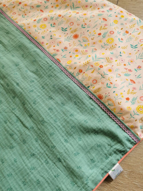 couverture pour bébé fille aux couleurs estivales, un tissu double gaz vert d'eau et un tissu fleuri sont réhaussés d'une dentelle parme et d'un liseret orange une création 2 Pommes et un mammouth
