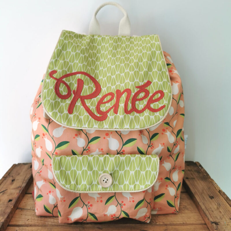 sac à dos maternelle personnalisable, orange avec des fleurs et vert avec des feuilles, des couleurs lumineuses et tendres. Sac conçu pour développer l'autonomie de l'enfant, fabriqué à la main de manière artisanale, made in france, made in cantal, une crétation 2 pommes et un mammouth