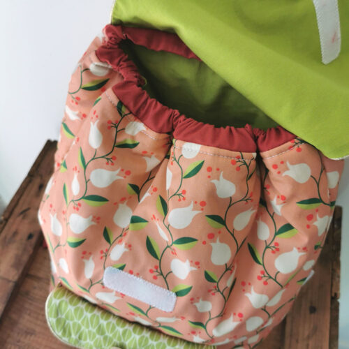 sac à dos maternelle personnalisable, orange avec des fleurs et vert avec des feuilles, des couleurs lumineuses et tendres. Sac conçu pour développer l'autonomie de l'enfant, fabriqué à la main de manière artisanale, made in france, made in cantal, une crétation 2 pommes et un mammouth