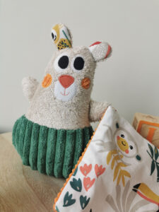 doudou pour bébé fait à la main de façon artisanal, une petit ours Dodu orange et vert, moelleux et doux qui procéde de nombreuses textures pour éveiller le sens du toucher de bébé, une création 2 pommes et un mammouth