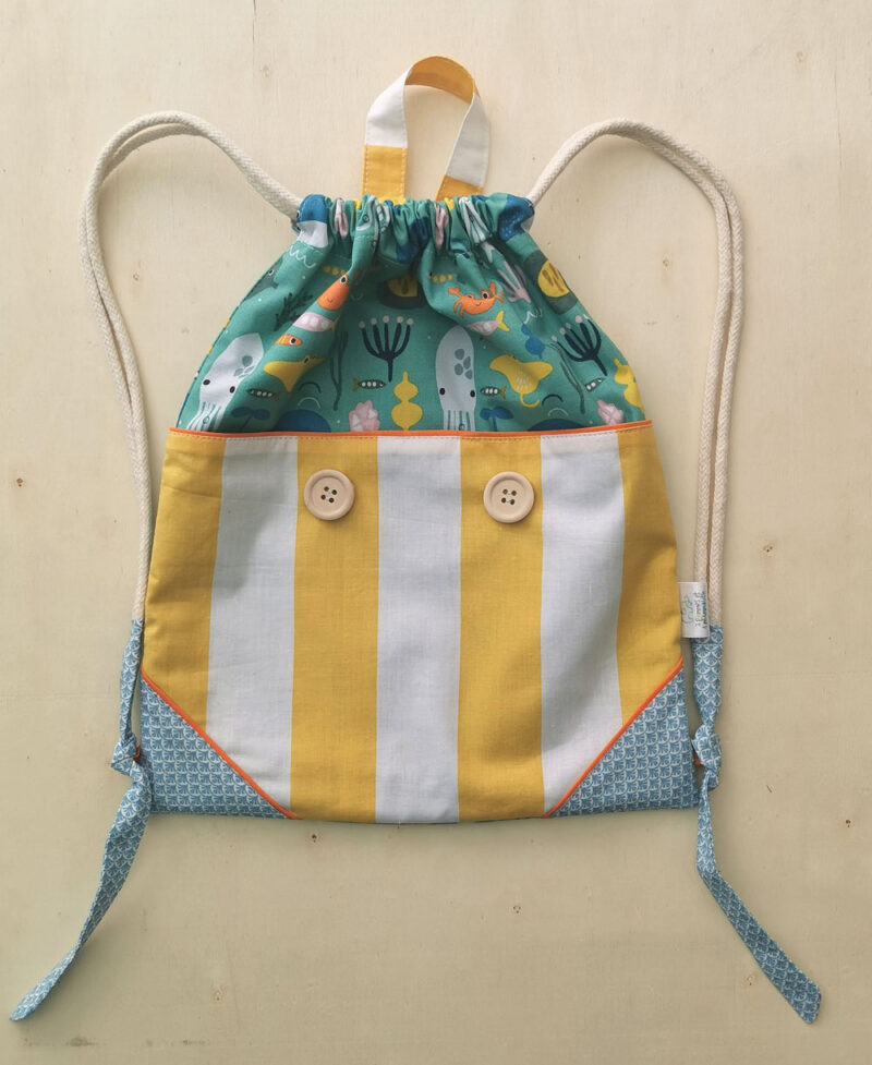 sac à dos ficelle pour enfant fabriqué à la main de façon artisanale, made in france, aux couleurs acidulées jaune, bleu et orange et des motifs poissons, crabes et calamars , une création 2pommes et un mammouth