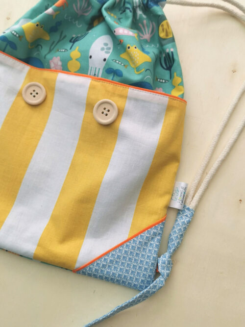 sac à dos ficelle pour enfant fabriqué à la main de façon artisanale, made in france, aux couleurs acidulées jaune, bleu et orange et des motifs poissons, crabes et calamars , une création 2pommes et un mammouth