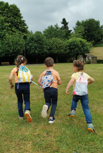 sac à dos ficelle pour enfant fabriqué à la main de façon artisanale, made in france, trois modèles différents portés par des enfants qui courent , une création 2pommes et un mammouth